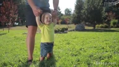可爱的蓝眼睛学步男孩在爸爸的帮助下在夏天公园的绿色<strong>草地</strong>上学习走路可爱的婴儿